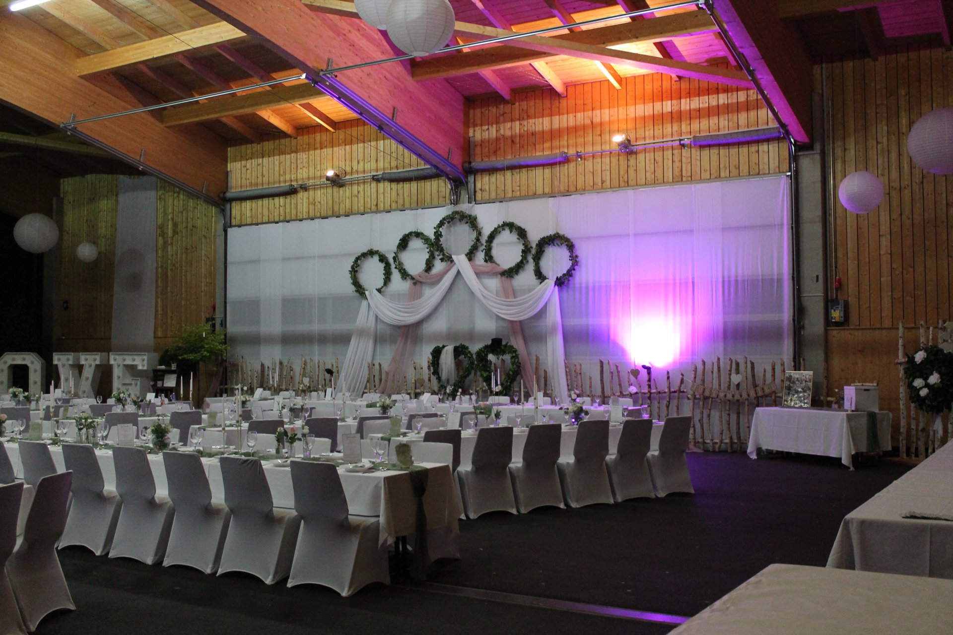 Festlich gedeckter Saal mit violetter und warmer Beleuchtung