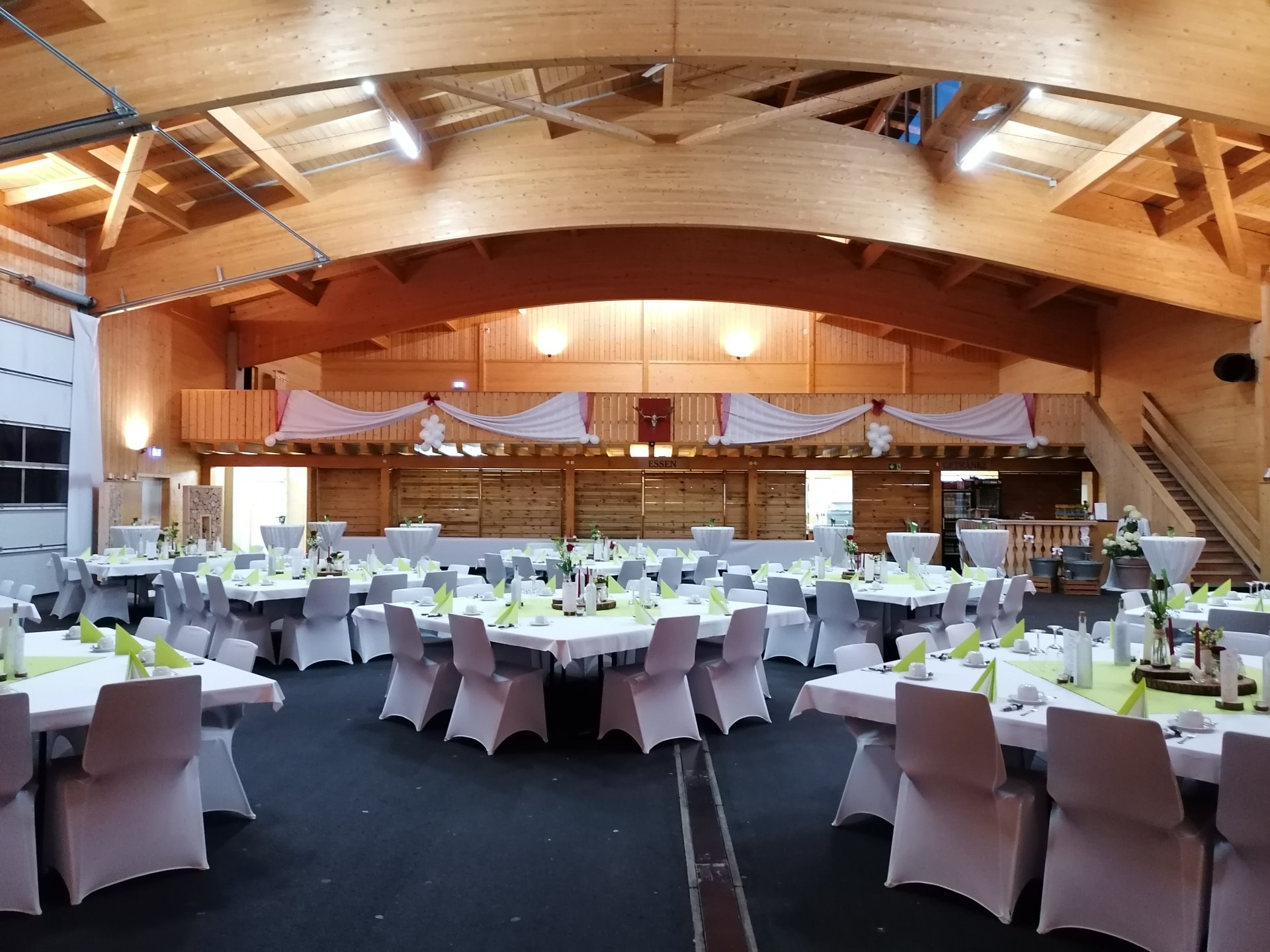 Festlich gedeckter Saal mit Bühne und Holzvertäfelung
