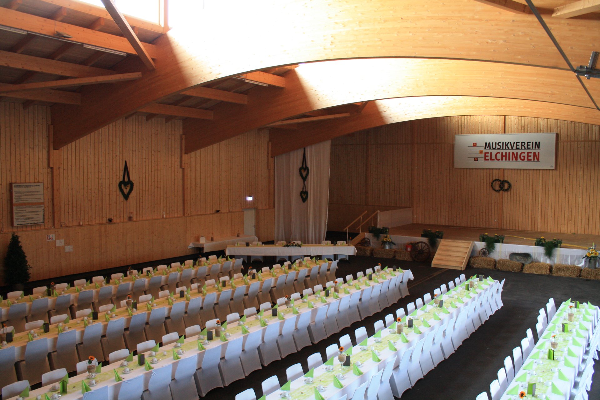 Festlich gedeckter Saal mit Bühne, Empore und langen Tischreihen
